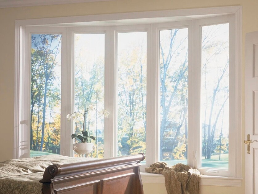 Luxury Utah bedroom with five tall white-framed picture windows showcasing autumn trees and natural light, featuring a wooden sleigh bed and white orchid arrangement